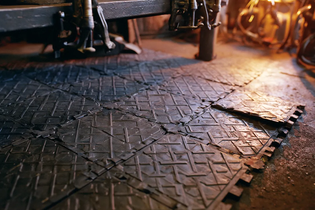 Interlocking fire-resistant floor tiles laid across a welding bay, showing the anti-slip tread and edge connectors